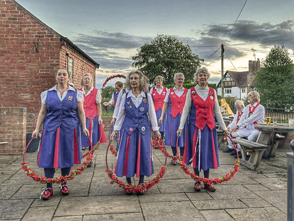 9 dancers lined up ready to dance holding their flower garlands