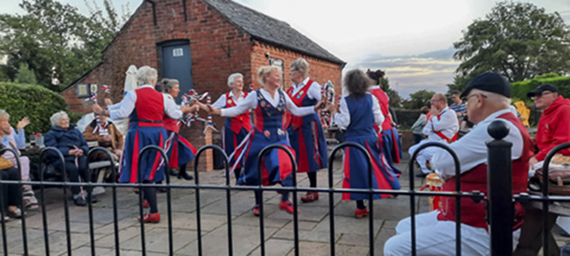 nancy butterfly dancing with an audience including white heart morris dancers watching on