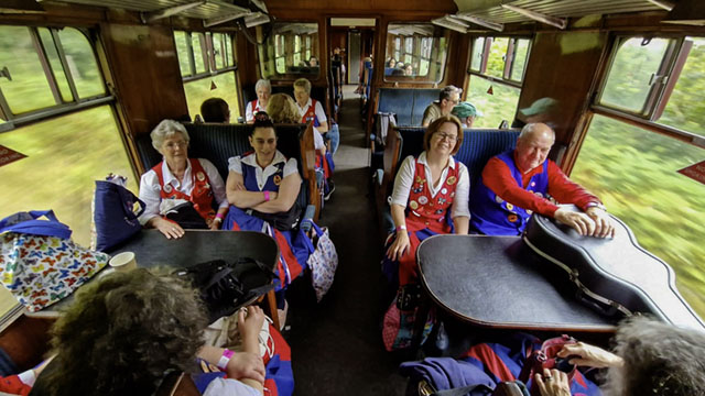 dancers seated at tables in a vintage carriage on moving train