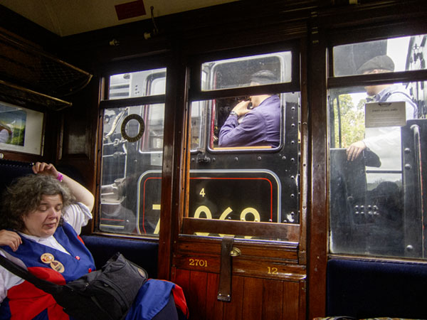 dancer leaning back in her luxurious first class seat. The windows are filled with an atmospheric view of an adjacent engine's footplate with its engineers waiting to start 