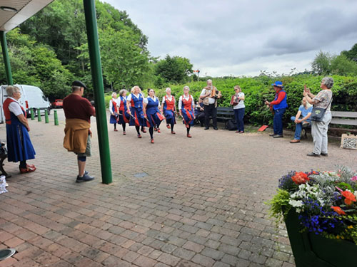dancers and musicians performing in front of the engine sheds in Highley with some interested spectators and photographers